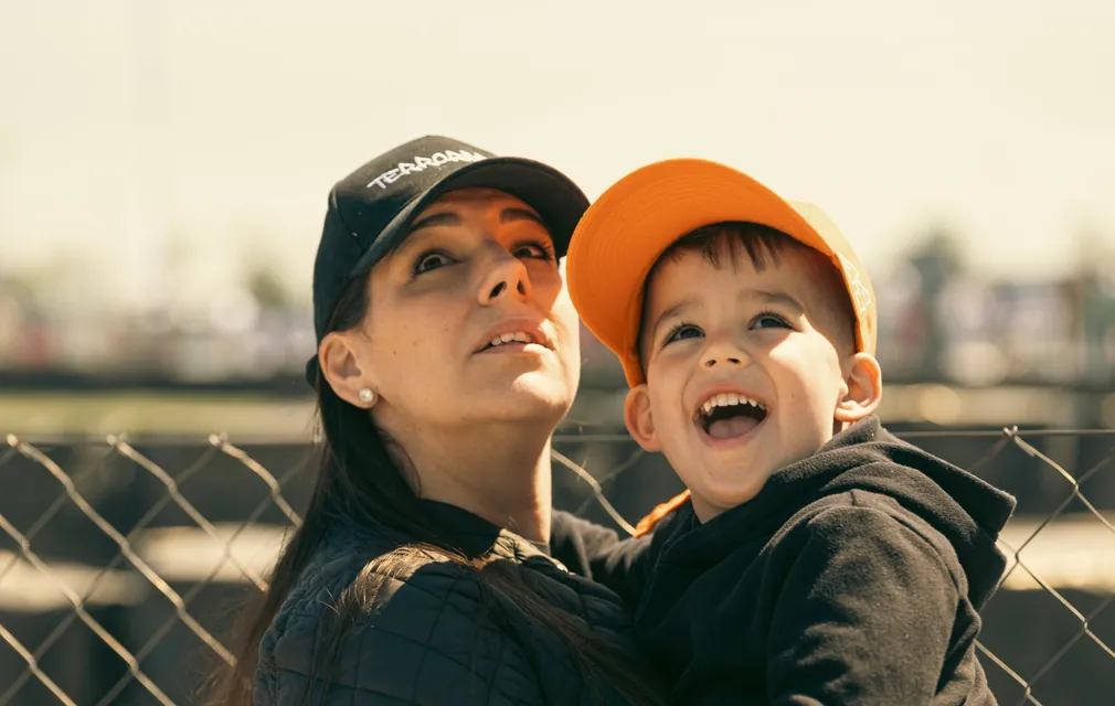 A mother and her little son laugh and look up behind the fence
