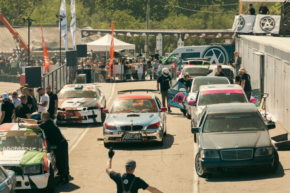 The pit lane with race cars, mechanics and spectators