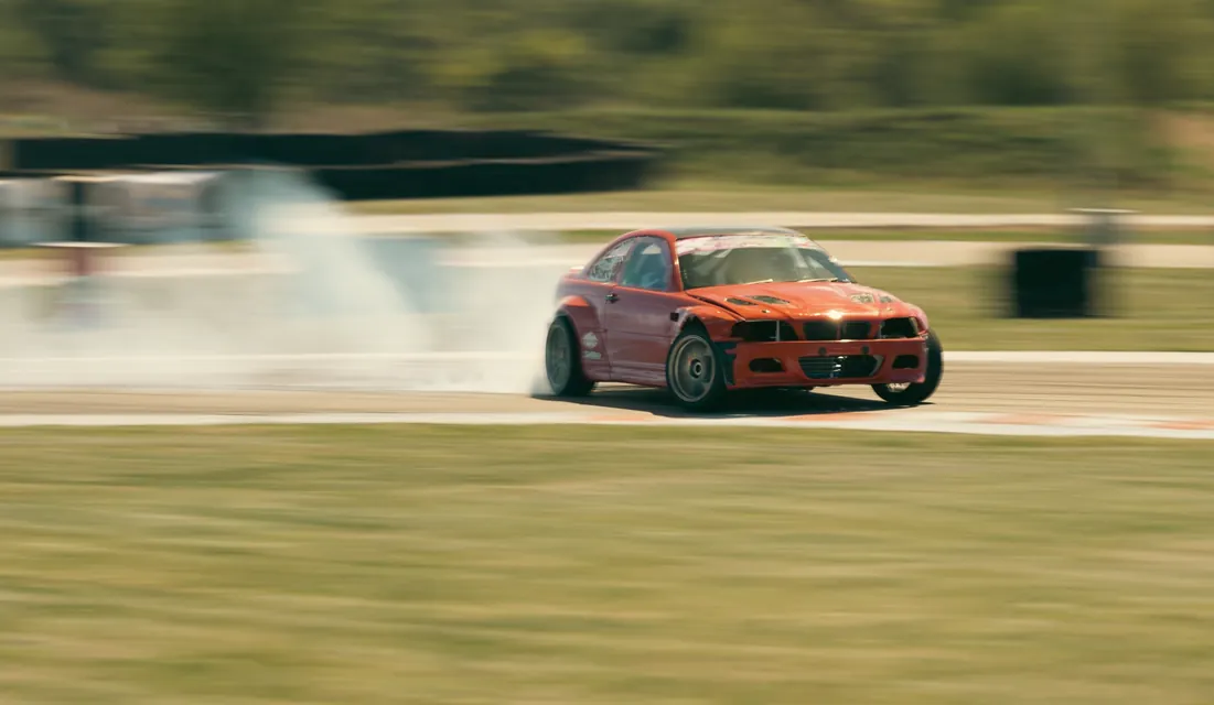 An orange BMW drifting with smoking tyres at APX 2026, Black Star Speedway, Visonta