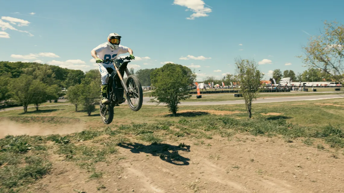 A rider jumps a dirt mound with the track in the background