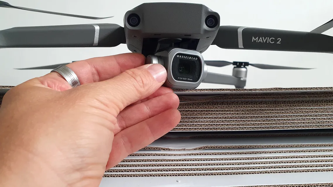 Mavic 2 drón kamerája kézben, hullámkarton köteg előtt a nyomdában