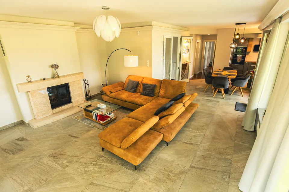 A spacious living room with a fireplace and corner sofa in natural light
