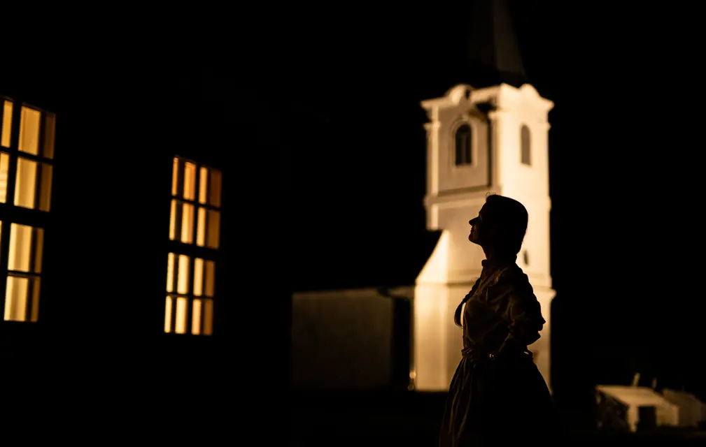 Sziluett egy kivilágított templomtorony előtt