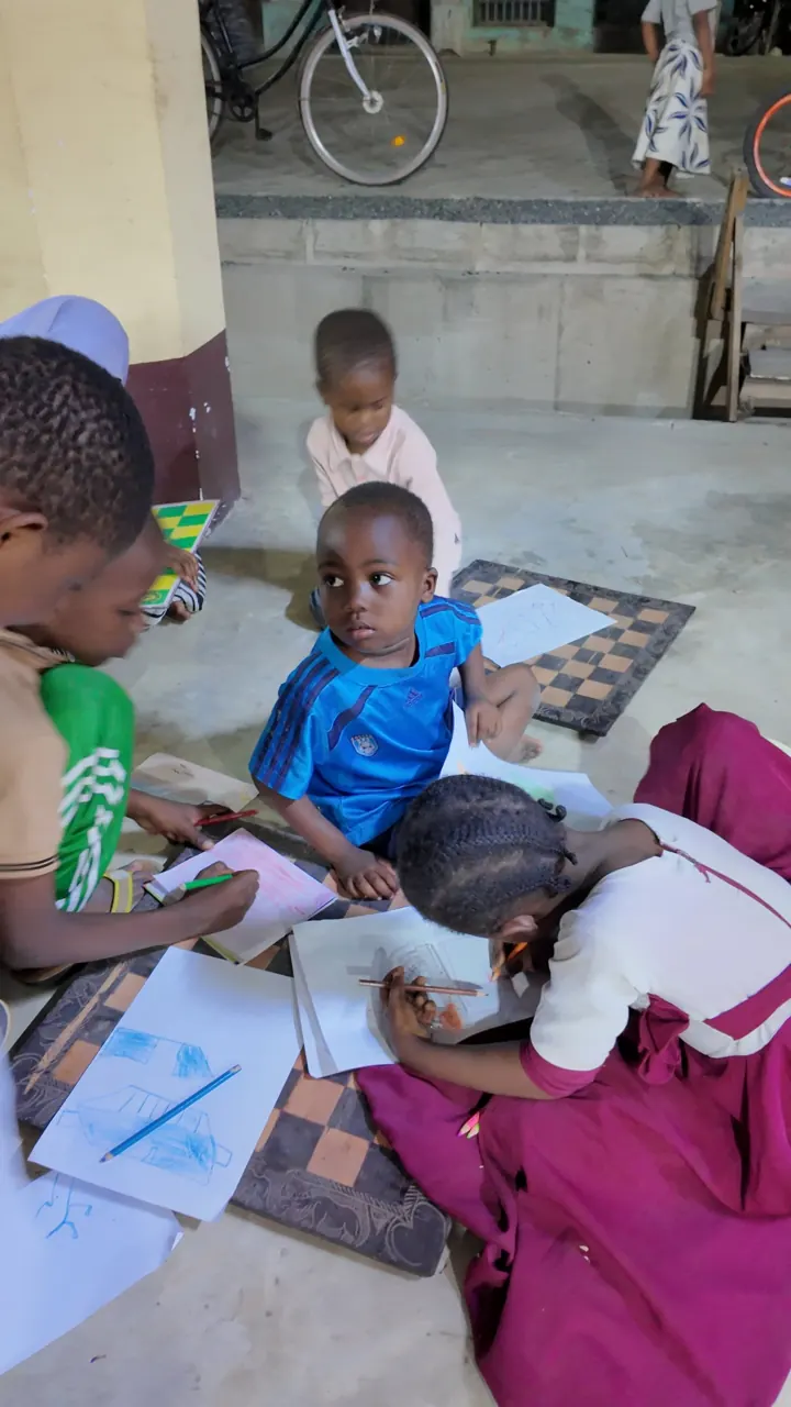 Children drawing on the floor, on sheets laid over chessboards